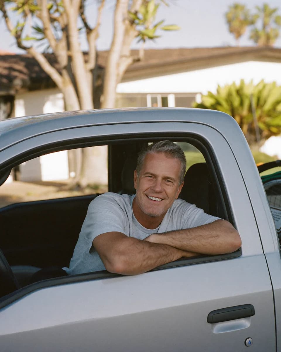 Pool technician smiling from the window of a white service truck